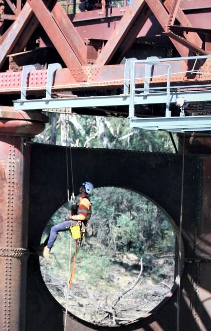 Worker abseiling off rail bridge