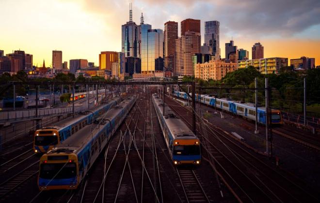 Melbourne's rail lines at sunset with city skyline.